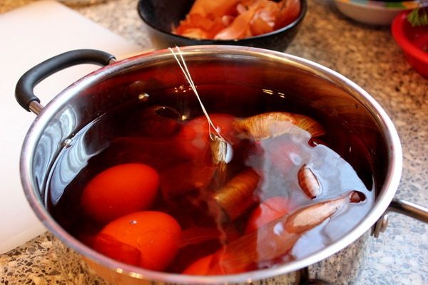 Hagymahéjak és fekete tea filtekek úsznak a fazékban a tojások körül