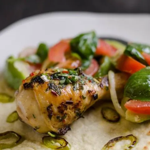 Jerk csirkecombok jalapenós lapos kenyérrel és bazsalikomos-avokádós paradicsomsalátával recept