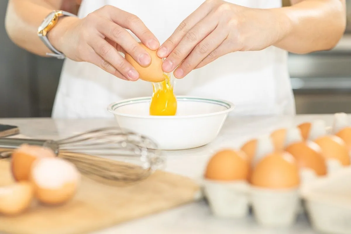 Young,Chef,In,White,Apron,Crack,Fresh,Egg,Yolk,Dropping