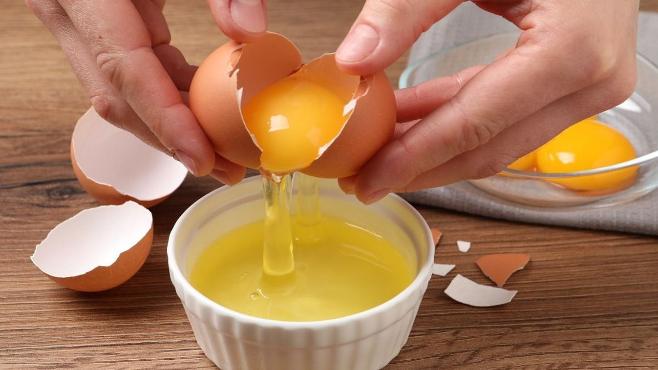 Woman,Separating,Egg,Yolk,From,White,Over,Bowl,At,Wooden