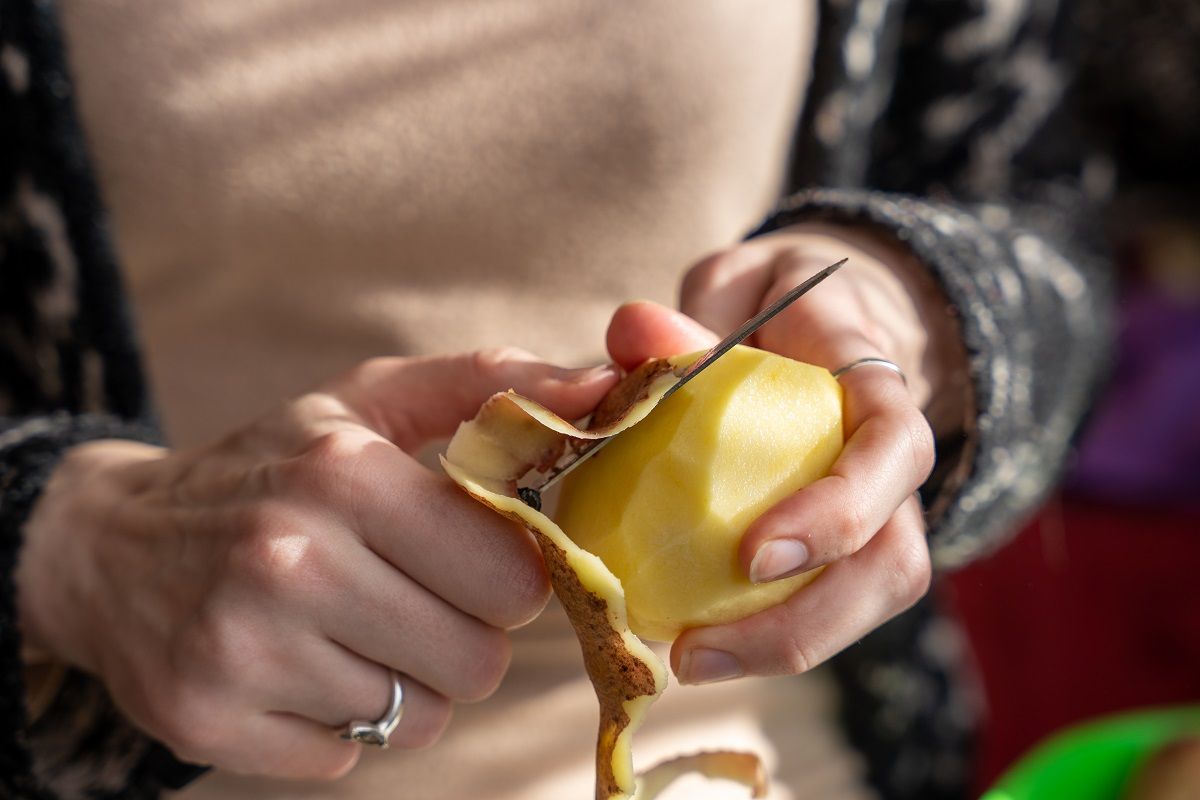 Close,Up,Of,Women,Holding,And,Peeling,Potato,With,A