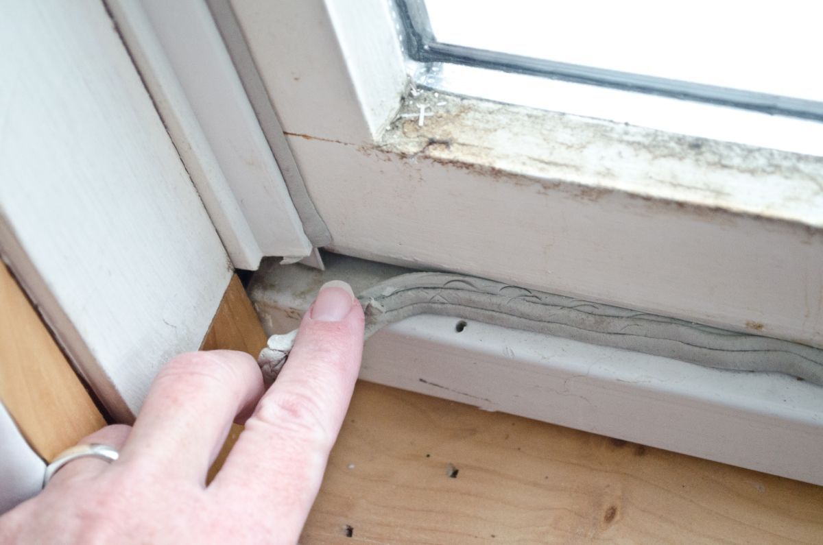 Caucasian,Woman's,Hand,Pressing,In,Grey,Caulk,In,Old,Window