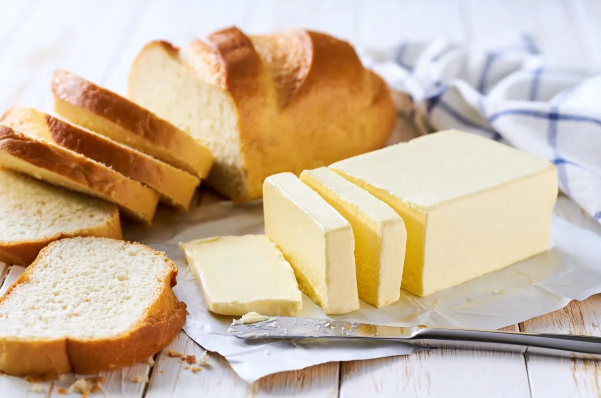 Cut,Slice,Wheat,Bread,With,Butter,On,A,Light,Kitchen