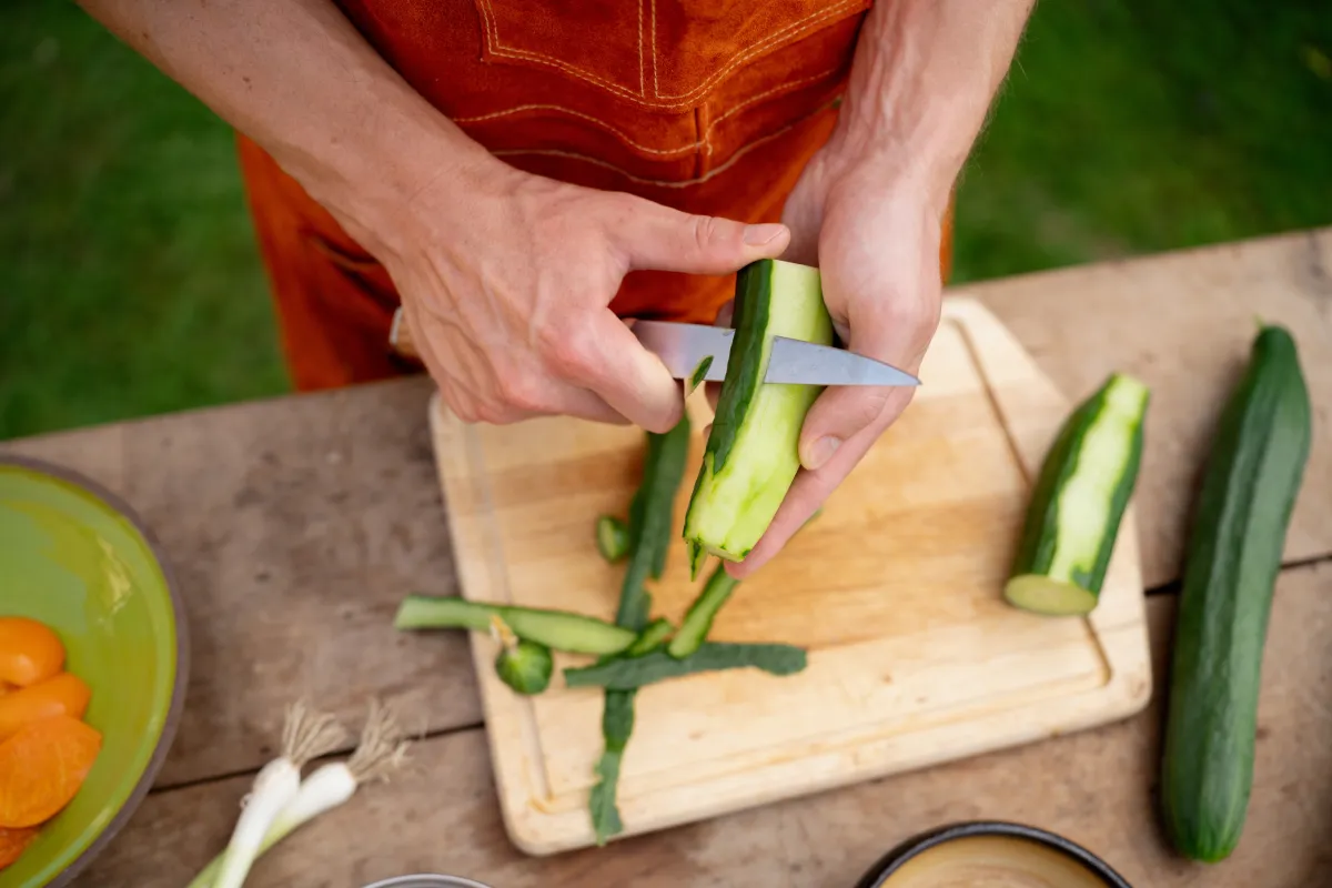 Close,Up,Of,Man,Holding,Sharp,Knife,,Peeling,Cucumber.,Preparing
