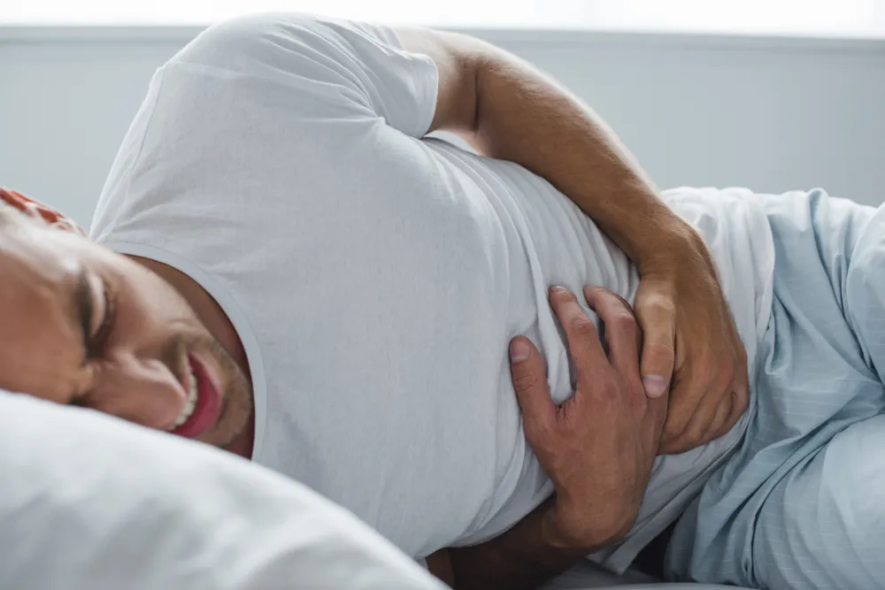 Cropped,Shot,Of,Man,Suffering,From,Stomach,Pain,In,Bed