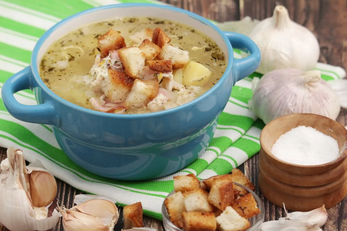 immunerősítő fokhagymaleves pirított kenyérkockákkal, egy füles edényben a konyharuhán