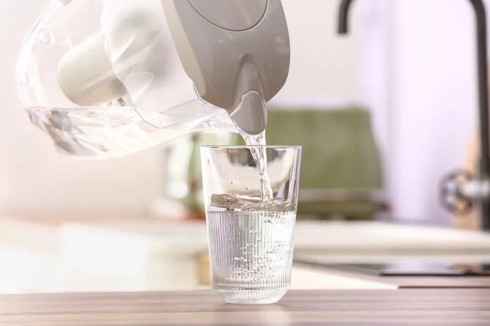Pouring,Of,Water,From,Modern,Filter,Jug,Into,Glass,On