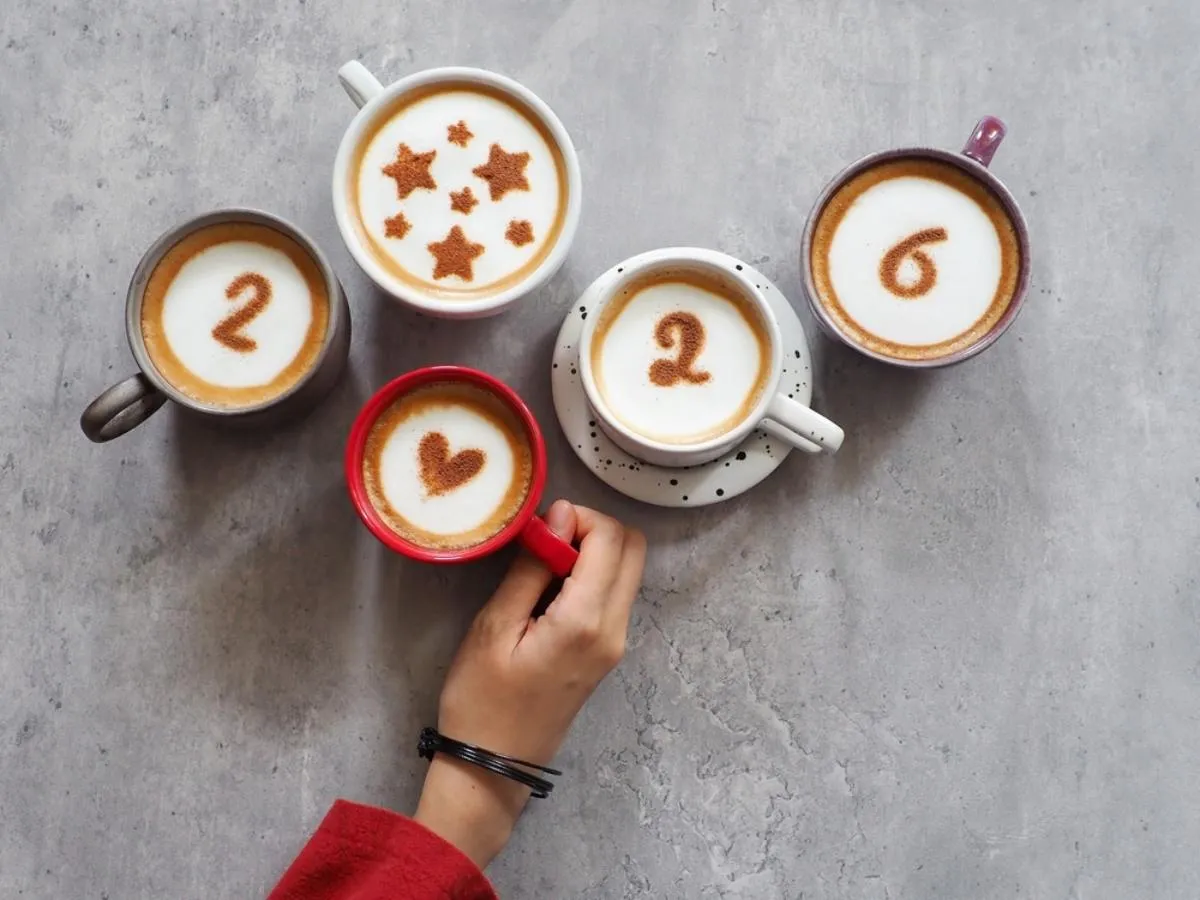 A horoszkóp 2026-ban is segít: egy női kéz, 5 csésze az asztalon, az évszám rajtuk a jövő év habból és az egyiken csillagok