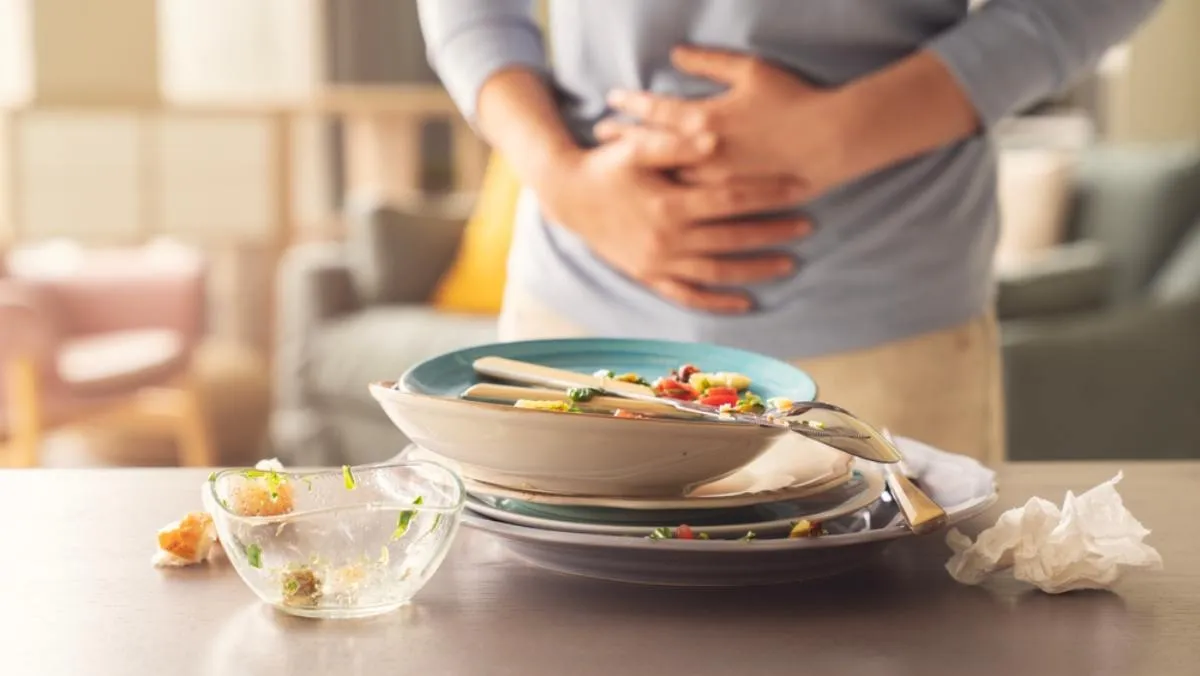 Gyomorpanaszok: üres tányérok előtt álló nő, aki a gyomrára szorítja a kezét