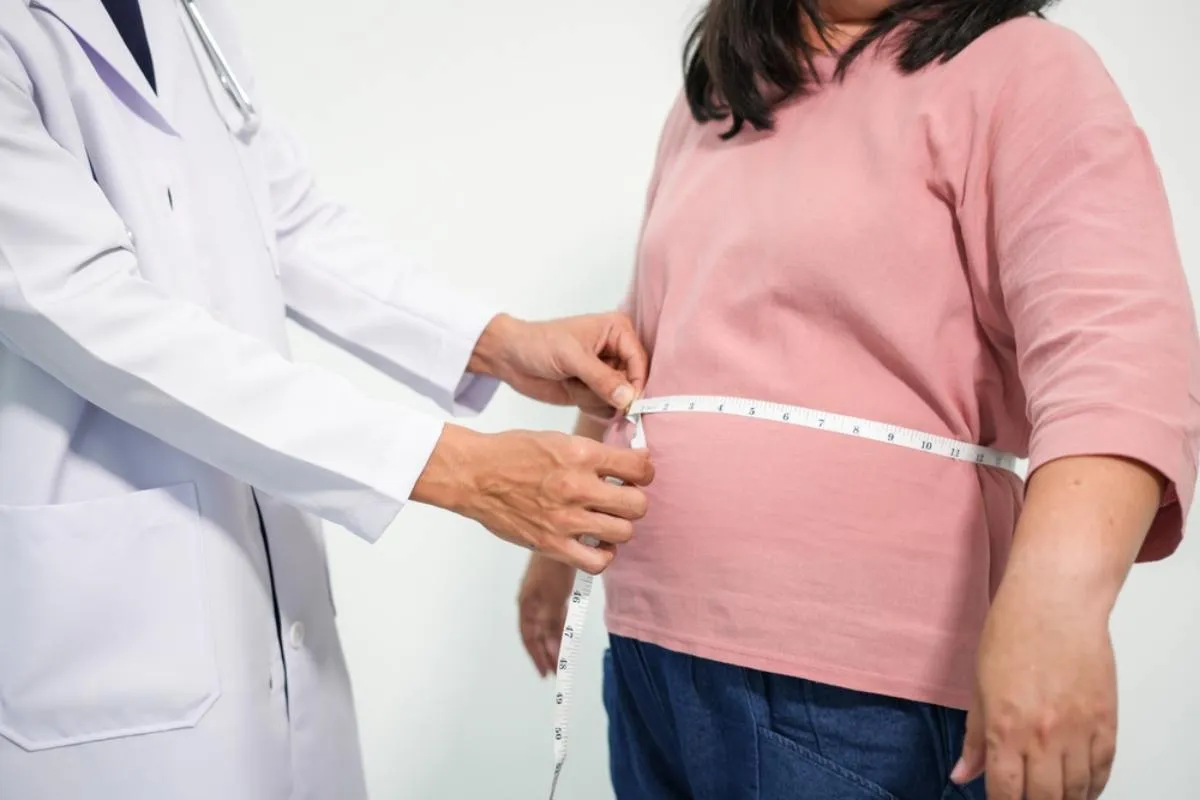 Zsigeri zsír: egy orvos mérőszalaggal méri egy női beteg hasának körfogatát