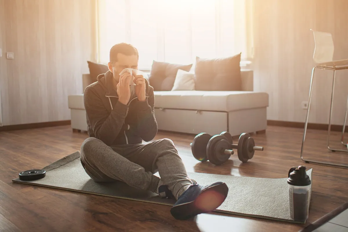 Férfi orrot fúj, miközben próbál betegen edzeni