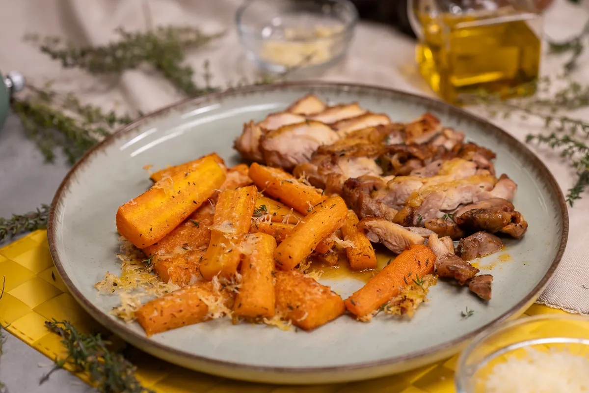 Sült csirkecomb és parmezános sült répa egy tányéron