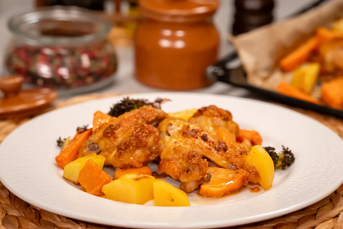 Parmezános sült csirkeszárny sült zöldségekkel egy tányéron