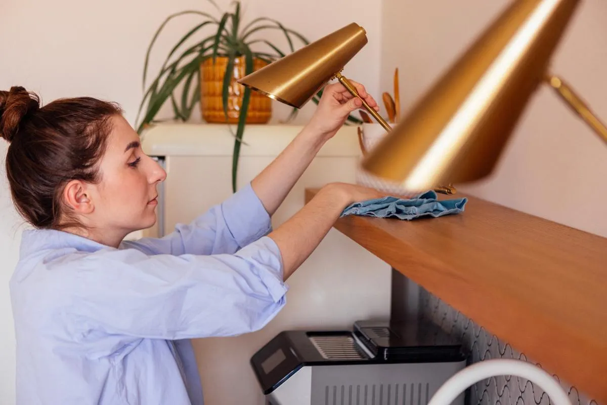 Por a lakásban: egy polcot portalanít egy nő