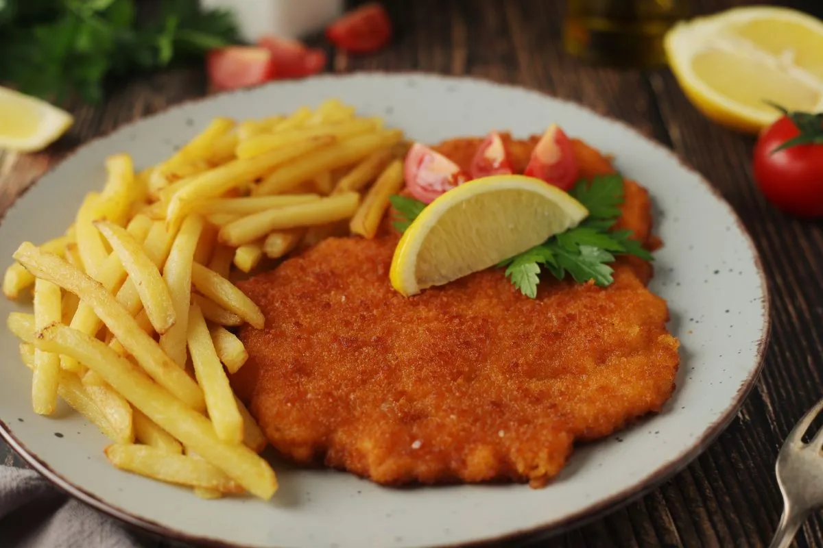 Egészséges bélflóra ellensége: egy fehér tányéron egy nagy szelet rántott hús és sült krumpli